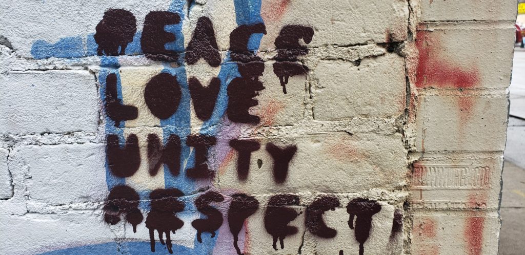 Peace Love Unity Respect spray painted on a building.